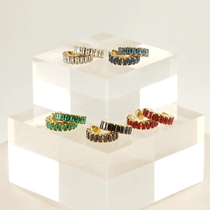 Close-up of gold C-shaped earrings with colorful zirconia stones on acrylic display blocks