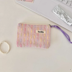 Nahaufnahme der rosa gewebten Kosmetiktasche mit Reißverschluss und lila Kordel auf dem Tisch