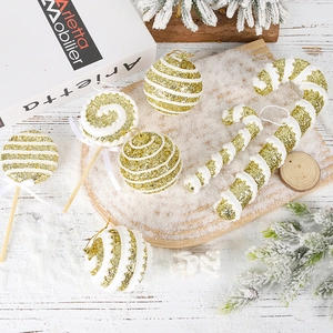 Golden glitter Christmas ornaments set with candy cane and lollipops on snowy tray