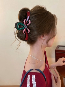 Gros plan d'une pince à cheveux chic en forme de nœud tricolore vert, rose et bordeaux