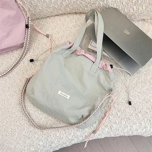 Details der graugrünen Tragetasche mit rosa Kordelzug und geflochtenem Schultergurt