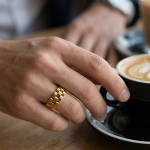 Close-up of gold watch chain style ring worn by a man holding a coffee cup