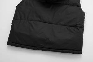 Close-up of black quilted hooded vest showing detailed horizontal stitching and matte fabric
