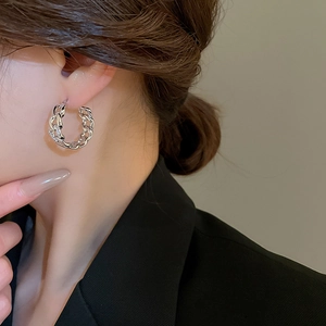 Close-up of a silver-tone interlocking chain earring with zircon inlay worn on a model