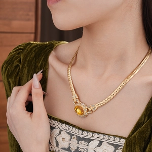 Detail of vintage gold necklace with oval amber gemstone and rhinestones on a model