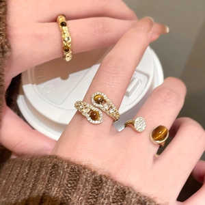 Detail of 18K gold plated tiger eye ring with zircon accents on a female hand