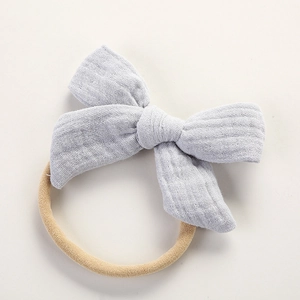 Détail d'un bandeau pour bébé en mousseline bleu clair avec nœud en coton et ruban en nylon