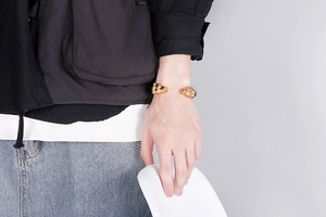 Detail of gold-plated wolf head open cuff bracelet on wrist for punk fashion style