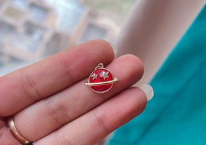 Macro shot of a mini red enamel planet pendant with gold star detail for DIY jewelry