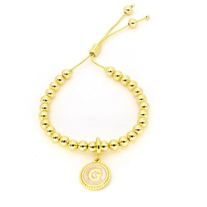 Détail du bracelet à perles dorées réglable avec pendentif lettre G en émail rose clair