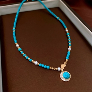 Detail of 18K gold plated necklace with turquoise beads, pearls and heart charm