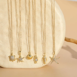 Detail of ocean-themed gold necklaces with zircon sea turtle, starfish and shell pendants