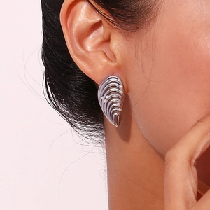 Détail de boucle d'oreille argentée texture coquillage avec perles blanches
