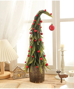 Miniature snow-dusted Christmas tree with red berries in a textured pot on a cozy table