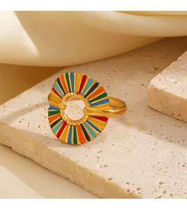 Close-up of golden geometric hollow ring with colorful enamel stripes on a stone base
