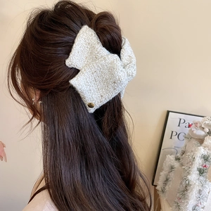 Close-up of white tweed bow hair claw clip showing texture and elegant style on hair