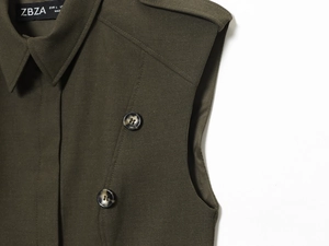 Detail of olive green sleeveless vest featuring epaulettes and marble-textured buttons