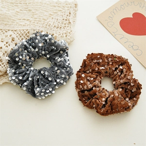 Detail of velvet scrunchies with shiny sequins in dark grey and brown colors
