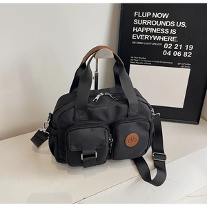 Detail einer schwarzen Nylontasche mit braunen Ledergriffen und Multi-Taschen-Design