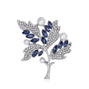 Dettaglio di spilla a foglia argento con strass marquise blu e perle bianche