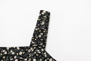Detail of ruched shoulder strap on black floral dress with white and yellow flowers