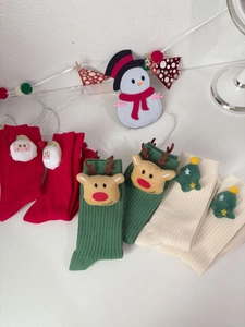 Close-up of knit Christmas socks with 3D Santa, reindeer, and tree plush decorations