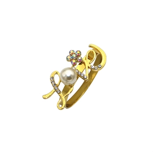 Detailed close-up of a gold LOVE napkin ring featuring a large pearl and crystal floral accent