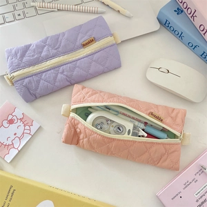 Quilted pastel pencil cases in lavender and peach pink on a clean desktop setup
