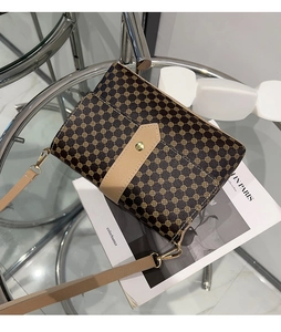 Close-up of vintage brown patterned crossbody bag with gold buckle on fashion magazines