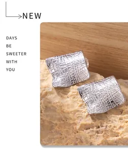 Detailed close-up of silver irregular square earring with a woven mesh texture on stone