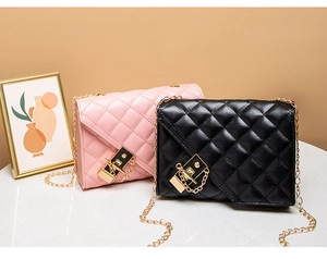 Detail view of black and pink quilted chain bags with gold hardware on marble surface