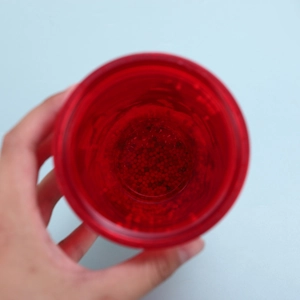 Close-up of a hand holding a red double-walled Christmas cup filled with water gel beads