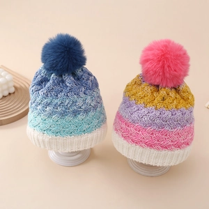 Detail of colorful knitted winter hats for toddlers with large fluffy pom poms