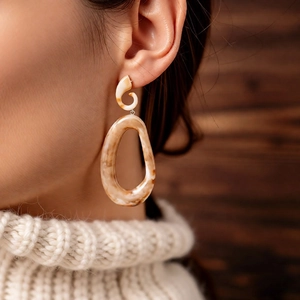 Close-up of vintage amber and beige acrylic oval drop earrings on model's ear