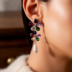 Détail de boucles d'oreilles fleuries plaquées or 18 carats avec perle et cristaux