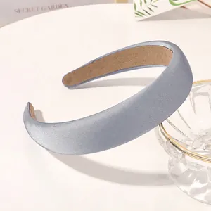 Detail of gray blue satin padded headband with brown non-slip lining on white surface
