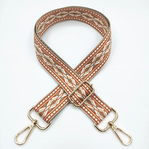 Macro detail of geometric jacquard shoulder strap with golden metal lobster clasps