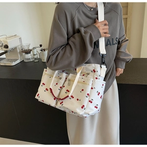 Detail of white canvas tote bag with cherry print showing large capacity and zipper pockets