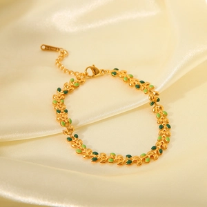 Detailed macro view of gold olive leaf bracelet with green enamel on silk background