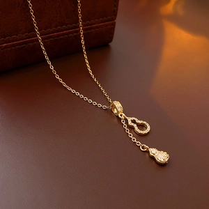 Détail d'un collier doré avec pendentif calebasse et zircons sur cuir sombre