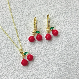 Nahaufnahme des roten Kirsch-Schmucksets mit Halskette und Ohrringen in Goldoptik