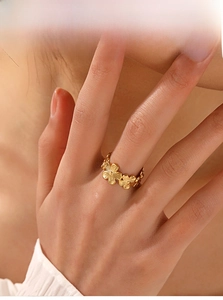 Close-up of golden adjustable daisy flower ring with brushed metal texture on finger