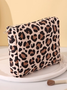 Leopard print cosmetic bag with zipper on a white decorative plate with makeup brush