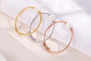 Détail de bracelets torsadés en perles empilés en finitions or, argent et or rose