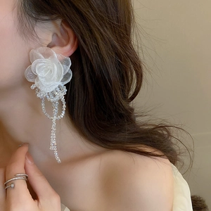 Gros plan de boucles d'oreilles fleur en organza avec perles de cristal sur modèle