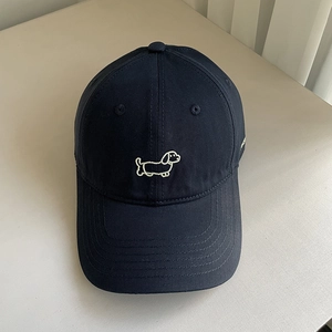 Detail of navy twill cotton baseball cap featuring a white embroidered dachshund pattern