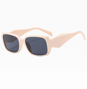 Detail view of cream square sunglasses featuring thick temples and dark grey lenses