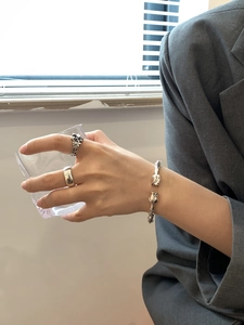 Macro detail of vintage silver tulip cuff bracelet and engraved rings on model's hand