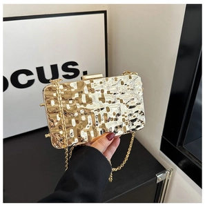 Detail of gold metallic clutch bag with lava texture surface and metal chain strap