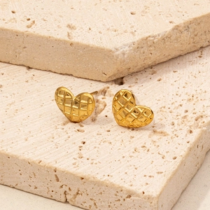 Detail shot of golden heart earrings with quilted pattern texture on stone base